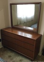 Full view of vintage wooden dresser with large mirror attached showing the entire unit in a corner room setting