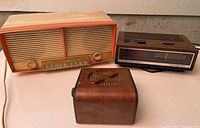 Electrohome AM/FM radio, General Electric digital clock radio, and vintage wooden speaker grouped together on a surface.