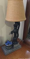 Close-up of the lamp showing the well pump design base and removable bucket with blue flowers, lamp shade off.