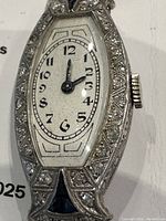 Front view of watch showing tonneau-shaped white gold case with diamond-set bezel and white enamel dial