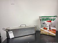 The same steamer pot shown from an angle with the boxed Italian stainless steel tomato press displayed beside it.