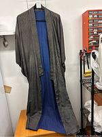 Full view of grey and blue men's kimono hanging, showing geometric patterned silk exterior and blue silk lining.
