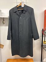 Front view of black Calvin Klein men's overcoat size 42 with all buttons fastened and hanging on wooden hanger.