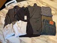 Overview of men's jackets, shirts, and pants laid out showing the variety and condition of items.