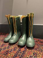 Front view of two pairs of green men's rain boots, sizes 9 and 10, lace-up tops with orange drawstrings.