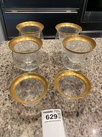 Set of 4 crystal shrimp cocktail glasses with wide, rounded bowls on stems, each with thick gold rims. Two extra gold rimmed liners shown separately in front; one liner has a chip.