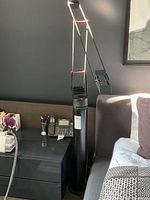 Full view of black Artemide Tizio 35 floor lamp in front of dark wall showing base, arms and head