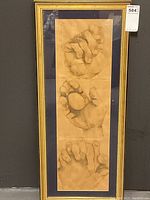 Full view of framed hand drawing showing three hand sketches and long gold frame with chip on one side