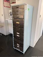 Three-quarter view of full cabinet showing painted exterior, stainless drawers, and caster wheels