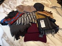 Winter scarves and knit hats arranged on marble surface including burgundy Ralph Lauren scarf