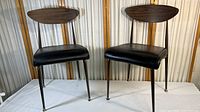 Pair of two mid-century modern Chromecraft chairs side by side showing black vinyl seats, wood backrests, and metal legs.