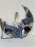 Full view of stained glass wizard sitting in crescent moon holding crystal scepter with chain.