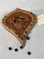 Full view of handcrafted wooden door harp with rose design and plucking strings ending in wooden beads.
