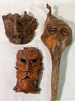 Overview of three carved wooden masks laid flat on white surface