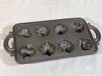 Full top view of the cast iron pan showing 8 vegetable shaped baking molds in a rectangular pan with decorative handles.