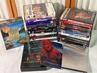 Photo showing the majority of the DVDs stacked in two piles and a few special boxes laid out in front, including Spider-Man 2 and T2 Ultimate Edition sets.