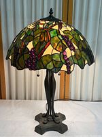 Full view of the stained glass table lamp showing grape vine design shade and metal base