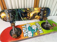 Two skateboards side by side showing top side of decks, trucks, and wheels