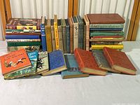 Full view of the collection of vintage children's books arranged on a table showing the variety in size, color, and condition.
