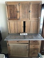 Front view of entire antique kitchen cabinet showing upper wooden doors, sliding tambour doors, metal countertop, drawers, and lower cabinet door.