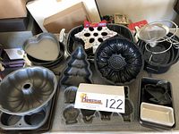 Various baking molds and pans including heart, Christmas tree, flower-shaped Bundt pan, mini loaf pans, and mesh strainer.