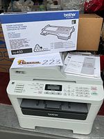 Brother MFC-7360N multi-function printer with unopened Brother TN-450 toner cartridge box on top plus instruction manuals displayed on printer.
