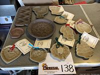 Overview photo showing all various ceramic cookie molds arranged on table, some with ribbons and original tags attached for festive/seasonal use