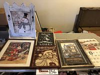 Six pieces of Christmas and winter themed wall art displayed on a table, showing various prints and a wooden snowman sign
