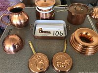Overview showing all copper cookware items laid out including water pitcher, double boiler, stockpot, rectangular pan, and round molds.