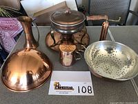 Photo showing entire collection of copper kitchenware including chafing dish, pitcher, colander, shaker, and pepper mill