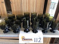 Eighteen green glassware pieces arranged in rows showing all sherbets, water goblets, and juice goblets from a front view