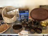 Photo showing the full set of wooden bowls, salt and pepper shakers, brass bowl, coffee maker box, baskets and glass items arranged on table.