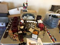 Overview of collected vintage Christmas items including candle holders, figurines, wooden sleigh with train, bagged ornaments, and bubble light Santa lamp.