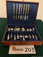 Full view of the opened wooden storage chest containing all the flatware pieces: knives, forks, spoons, serving utensils.