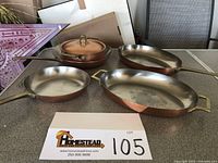 Overhead shot showing all five pieces: saucepan with lid, small frying pan, medium oval skillet and large oval roaster.