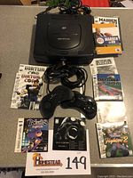 Photo showing Sega Saturn console, controllers, and six game cases with manuals arranged around it for identification.