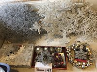 Wide view of large wire and glitter snowflakes, small snowflake ornaments, jingle bell wreath, candleholders and artificial pine sprays arranged for photographing.