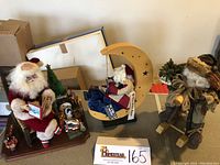 Wide angle shot of three Santa figurines including Lynn West Santa in rocker, Ye Old Santa Maker Santa on Crescent Moon, Old World Santa on wooden rocking horse.