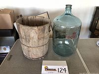 Wooden bucket from old ice cream maker next to large glass bottle