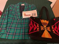 Black Pendleton tote bag with colorful orange, red, and yellow geometric tribal patterns and black shoulder straps, shown alongside jacket