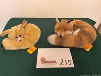 Two curled fox plush toys Fenny and Fuzzy on green table with visible tags and lot card.