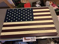 Top-down view of the wooden American flag wall art on a table showing the painted red, white, and blue with fifty white stars.