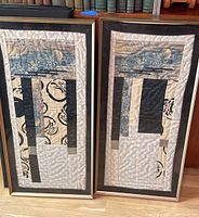 Two framed textile art pieces standing side by side, showing overall size and framing style
