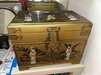 Front view of the rectangular golden enameled jewelry box showing detailed chinoiserie painting and metal lock