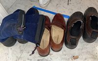 Photo showing three pairs of men's shoes on floor: blue drawstring winter boots, brown leather slip-ons, and brown rubber-soled duck boots.