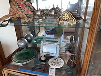 Glass display case with various decorative items including globes, plates, frame, wood duck figurines