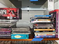 Shelf with stacks of DVDs and Blu-rays showing various movie titles and cases