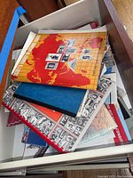Drawer containing assorted stamp albums, maps, and ephemera items, showing the Scott's Family of Nations Album on top.