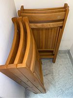 Stack of four wooden folding chairs showing their structure and finish