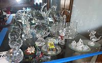 Wide shot showing multiple glass figurines including spheres, animals, flower shapes, and buildings